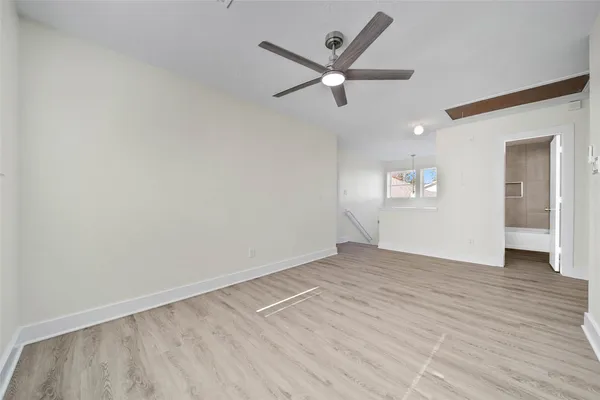 an empty room with wooden floor fan and windows