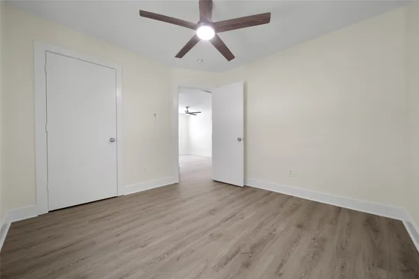 an empty room with wooden floor a ceiling fan and closet
