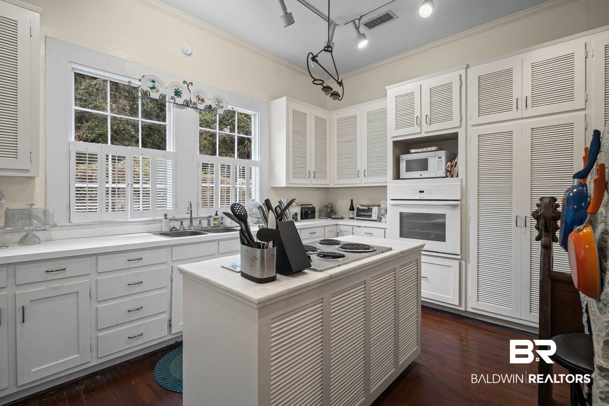 23561 Main Street Fairhope, AL 36532 - Photo 8 of 45 Kitchen with white cabinets, a kitchen island, light countertops, ornamental molding, and white appliances