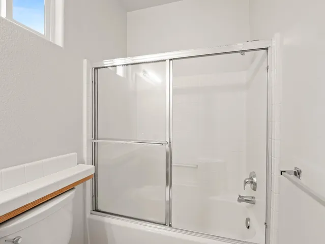 an empty room with a window and a ceiling fan