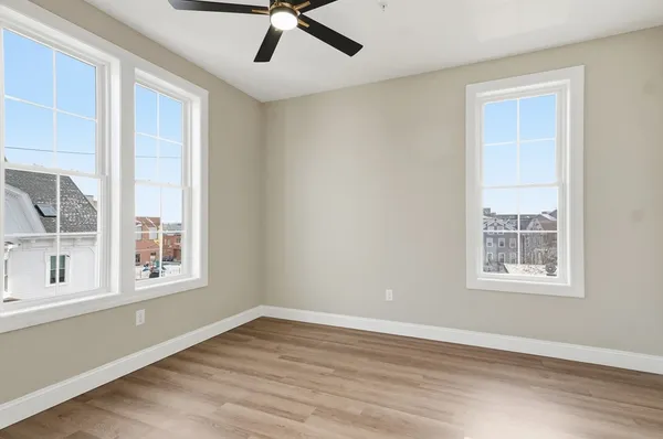 an empty room with wooden floor and windows