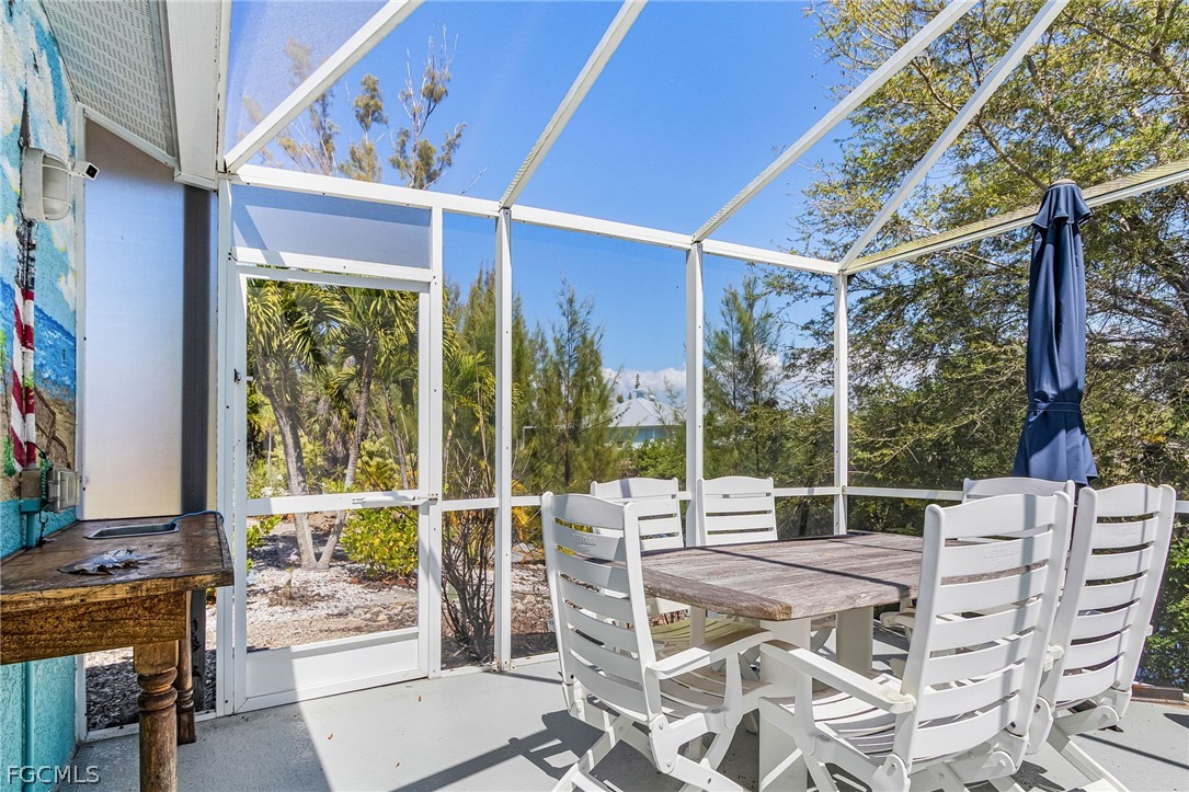 3852 Stabile Road St. James City, FL 33956 - Photo 21 of 27 a view of a patio with a table chairs and a floor to ceiling window