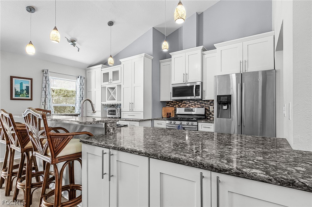 3852 Stabile Road St. James City, FL 33956 - Photo 8 of 27 a kitchen with stainless steel appliances granite countertop a stove a sink a refrigerator white cabinets with a dining table and chairs