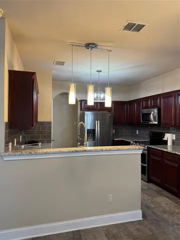 a kitchen with stainless steel appliances granite countertop a sink a stove and a refrigerator