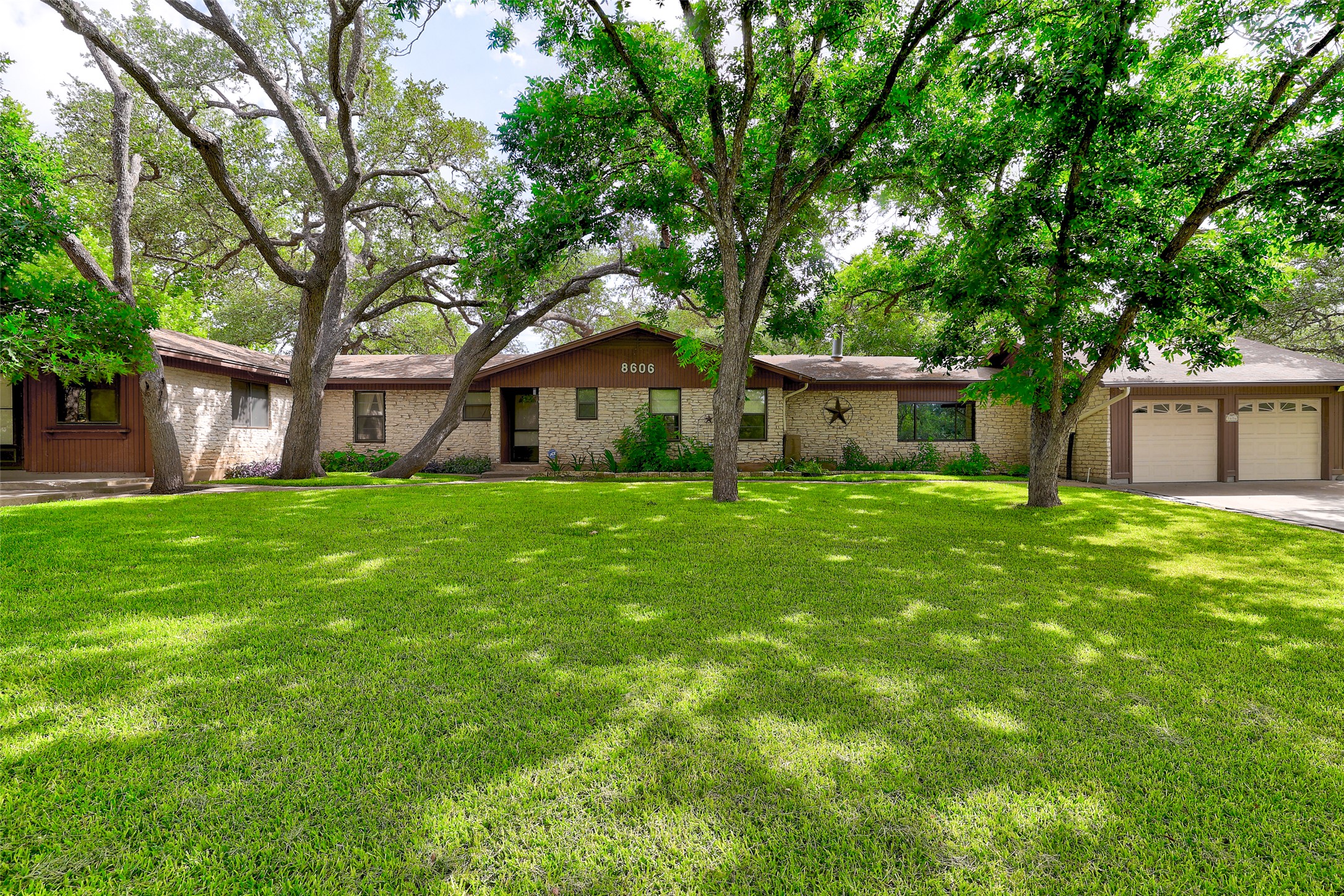 Mature trees shade this charming residence with a broad, manicured lawn, attached garage and carport