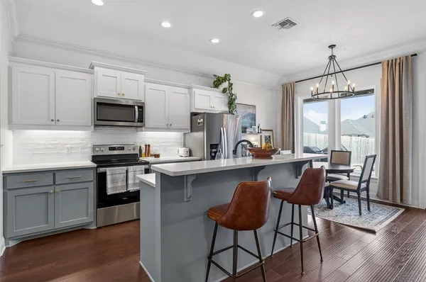 a kitchen with stainless steel appliances granite countertop a stove top oven a sink a dining table and chairs with wooden floor