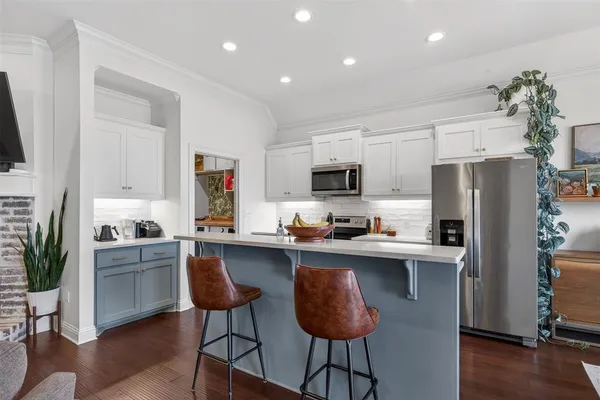 a kitchen with stainless steel appliances a sink a stove a refrigerator cabinets and a dining table