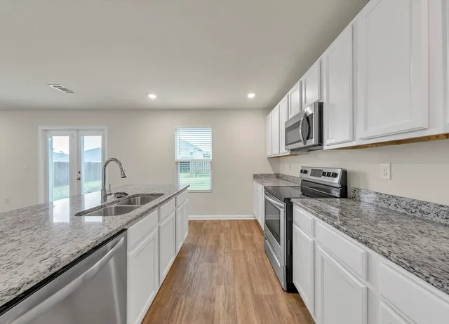 a kitchen with granite countertop a sink stove refrigerator and cabinets