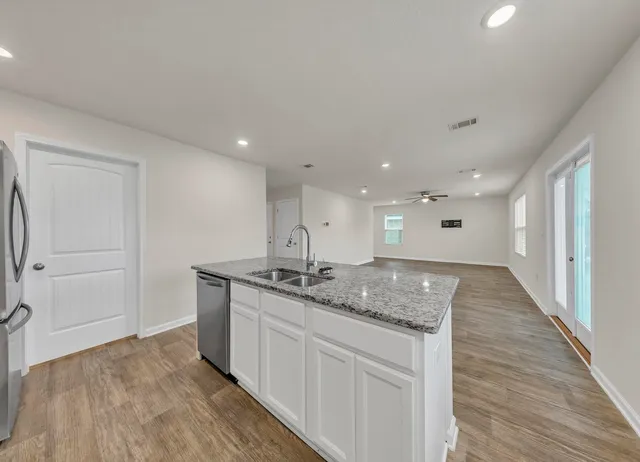 a view of kitchen island a sink wooden floor and a living room