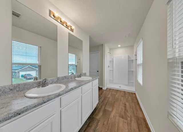 a spacious bathroom with a granite countertop sink a mirror and a shower