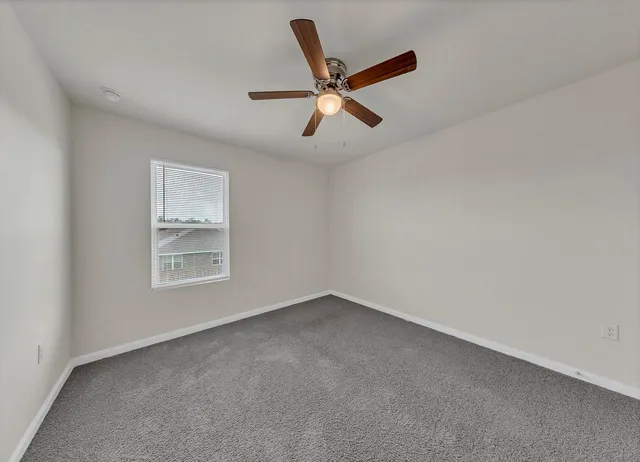 an empty room with ceiling fan and windows