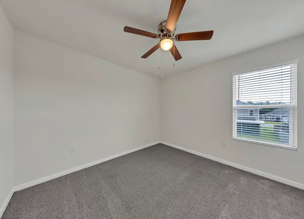 an empty room with a window and a fan