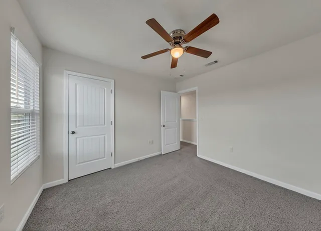 an empty room with windows and fan