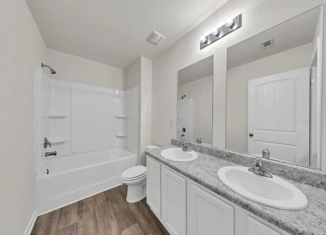 a bathroom with a granite countertop sink a toilet and shower
