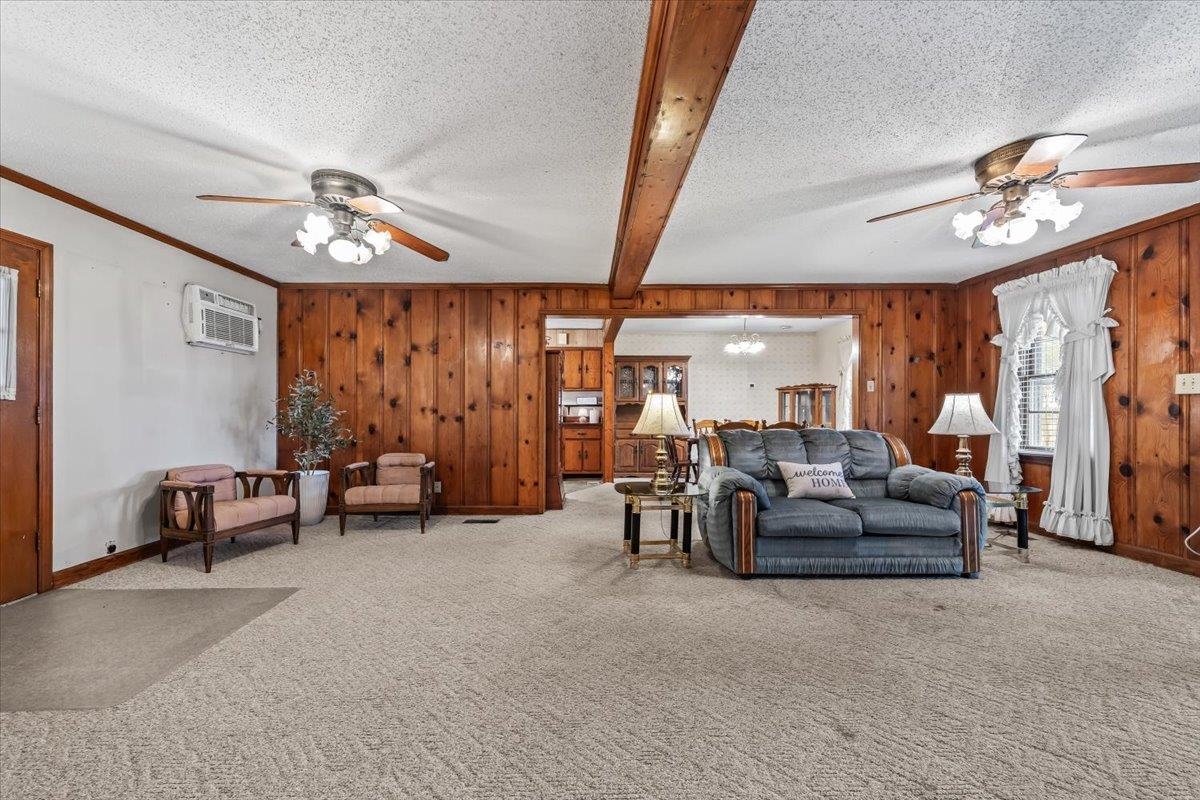 2972 Russell Bond Road Millington, TN 38053 - Photo 8 of 38 Carpeted living area featuring ceiling fan, beamed ceiling, a textured ceiling, a chandelier, and wooden walls