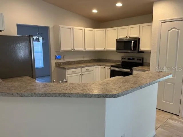 a kitchen with stainless steel appliances granite countertop a sink a microwave a refrigerator and white cabinets