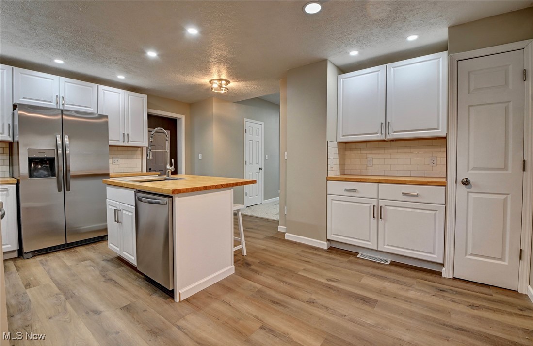 4624 Ridge Avenue Southeast Canton, OH 44707 - Photo 6 of 48 Kitchen featuring tasteful backsplash, butcher block countertops, appliances with stainless steel finishes, a textured ceiling, and an island with sink