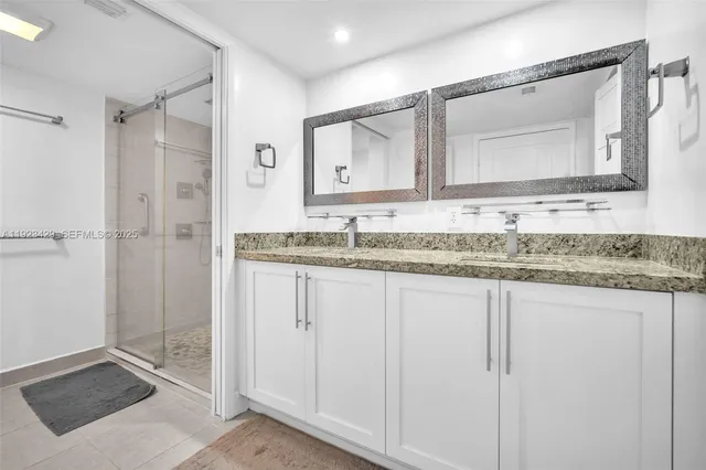 a bathroom with a granite countertop sink a mirror and a shower
