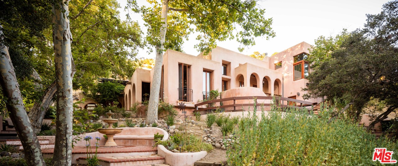23407 Red Rock Road Topanga, CA 90290 - Photo 1 of 41 a view of a white house with a fountain and plants