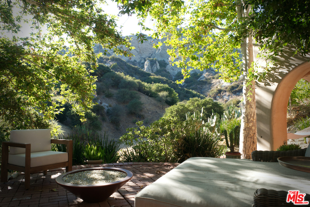 23407 Red Rock Road Topanga, CA 90290 - Photo 38 of 41 a backyard of a house with table and chairs and a large tree