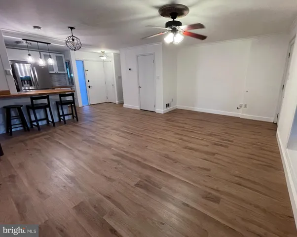 a kitchen with stainless steel appliances granite countertop a refrigerator a sink dishwasher a stove and a dining table with wooden floor