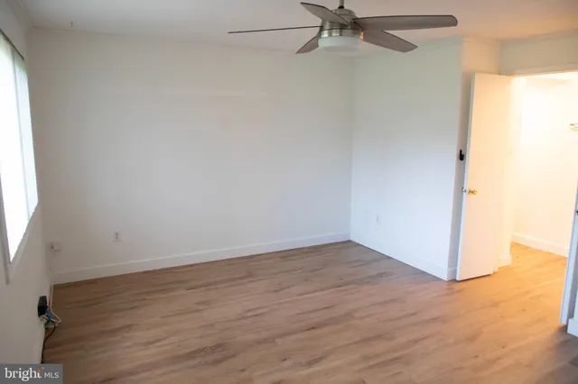 a view of an empty room with wooden floor and closet