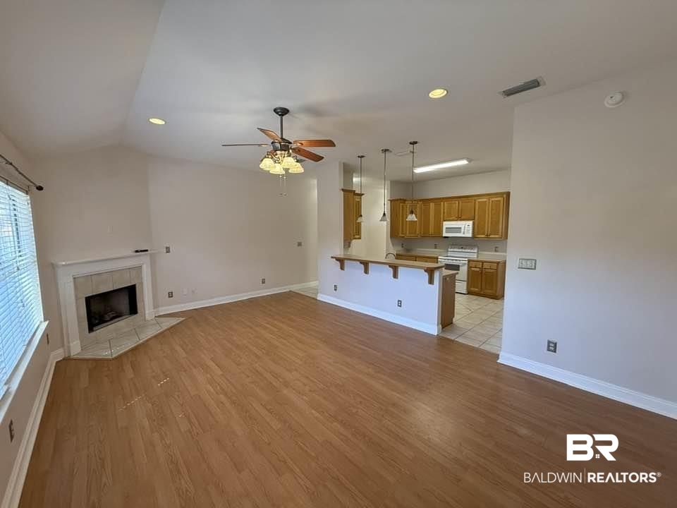 10428 South Side Loop Fairhope, AL 36532 - Photo 13 of 28 Unfurnished living room with light wood finished floors, baseboards, visible vents, a ceiling fan, and a tile fireplace
