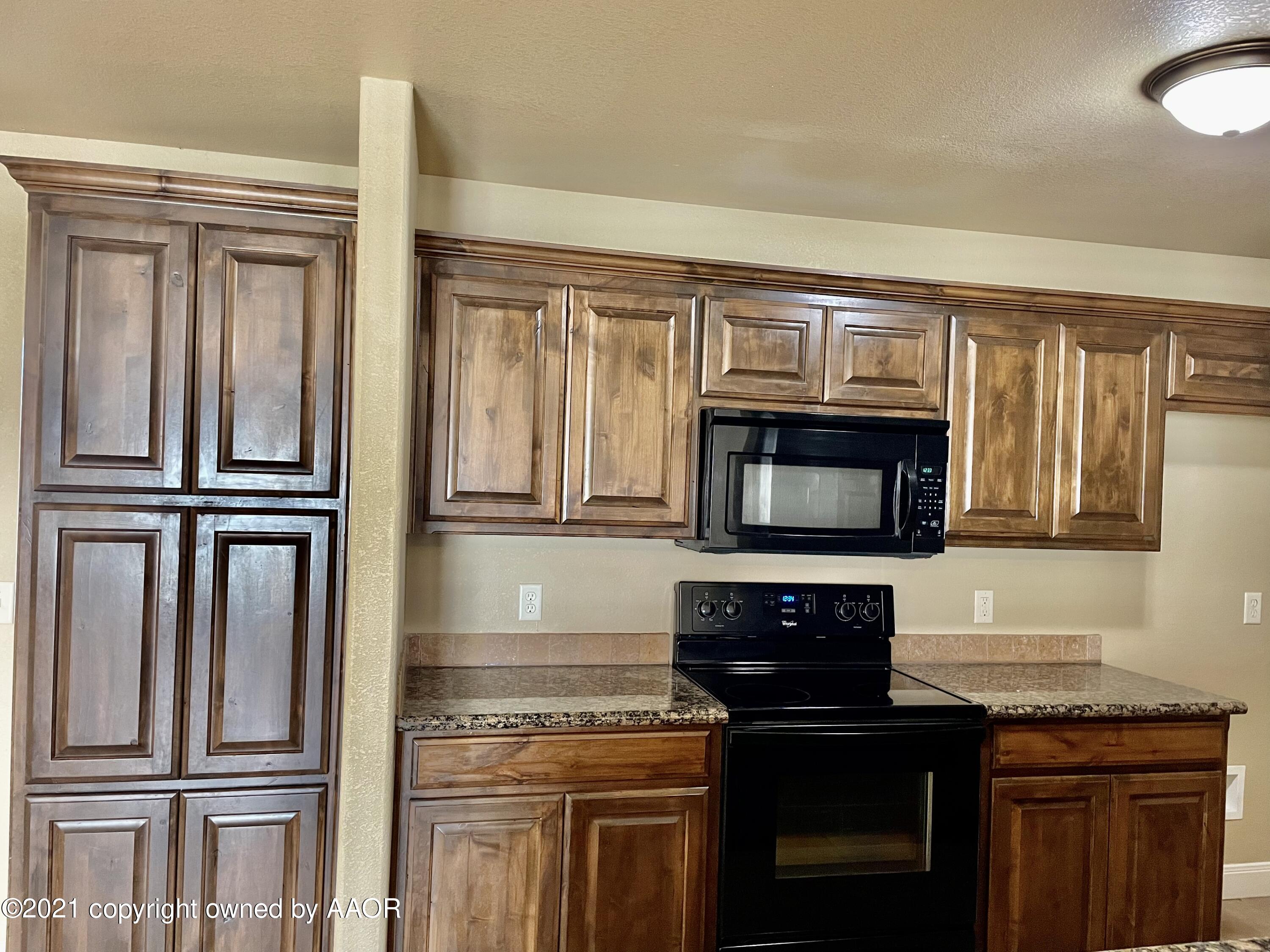 9812 Perry Avenue Amarillo, TX 79119 - Photo 2 of 15 a kitchen with granite countertop a refrigerator stove and microwave