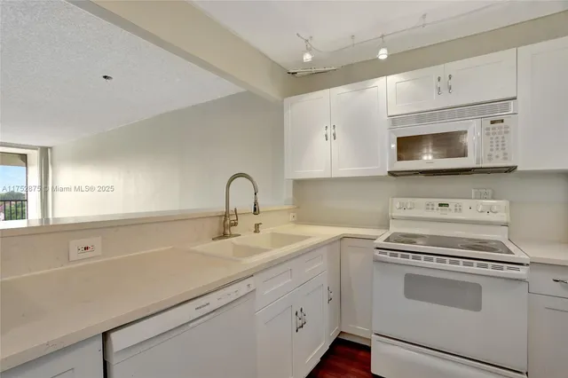 a kitchen with a sink dishwasher and white cabinets with wooden floor
