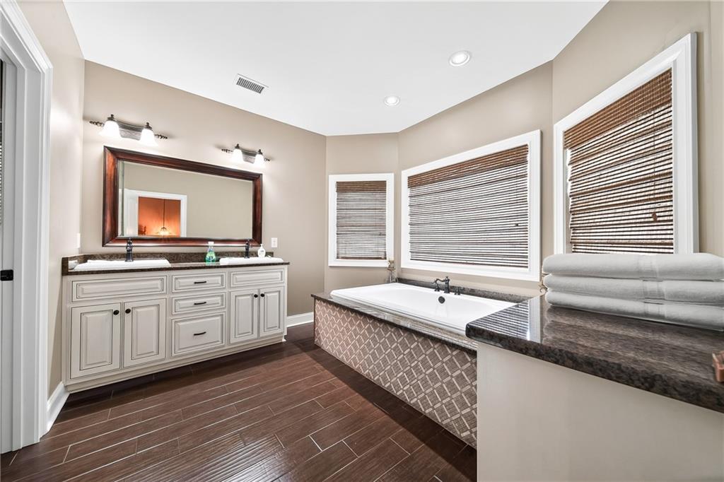 611 Padgetts Road Opelika, AL 36804 - Photo 28 of 64 Dual vanity with stone-finish countertop, wood-finish flooring, built-in soaking tub, and recessed lighting