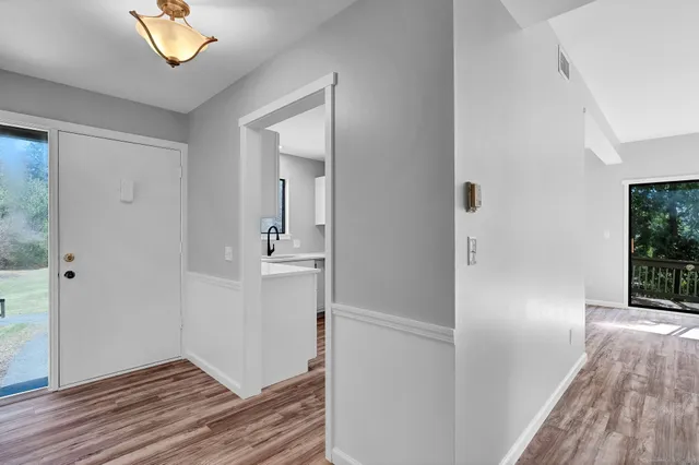 a view of a hallway with wooden floor and a bathroom