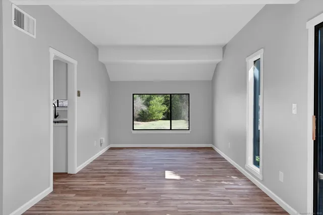 a view of an empty room with wooden floor and a window