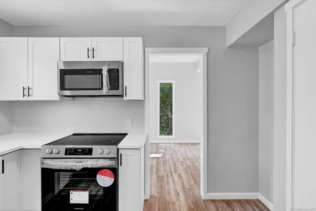 a kitchen with microwave a stove and white cabinets