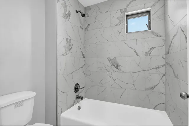 a bathroom with a white bath tub and a toilet