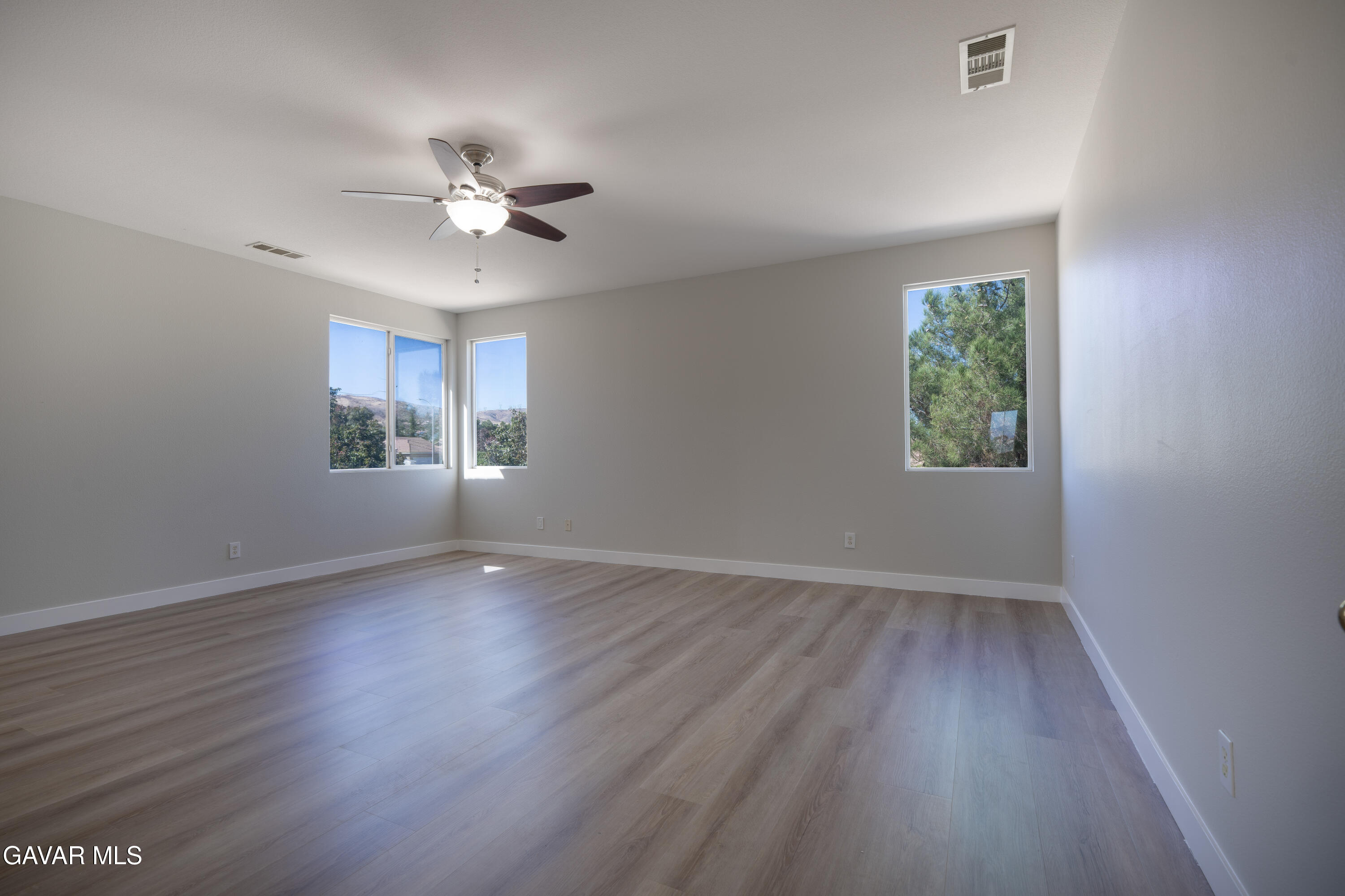 40271 Preston Road Palmdale, CA 93551 - Photo 16 of 38 an empty room with wooden floor chandelier fan and windows