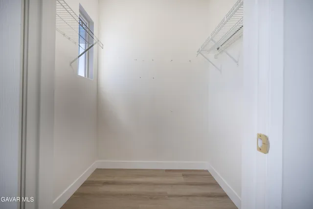 a view of an empty room with wooden floor ceiling fan