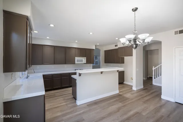 a spacious kitchen with stainless steel appliances granite countertop a sink a stove and a wooden floors