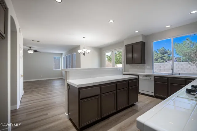 a kitchen with kitchen island granite countertop a sink a counter top space stainless steel appliances and windows