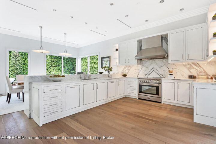 215 Indian Road Palm Beach, FL 33480 - Photo 7 of 32 a kitchen with stainless steel appliances kitchen island granite countertop a stove a sink and white cabinets with wooden floor