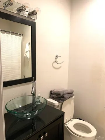 a bathroom with a granite countertop sink toilet and mirror