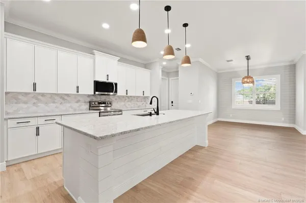 a large white kitchen with a sink and dishwasher with wooden floor