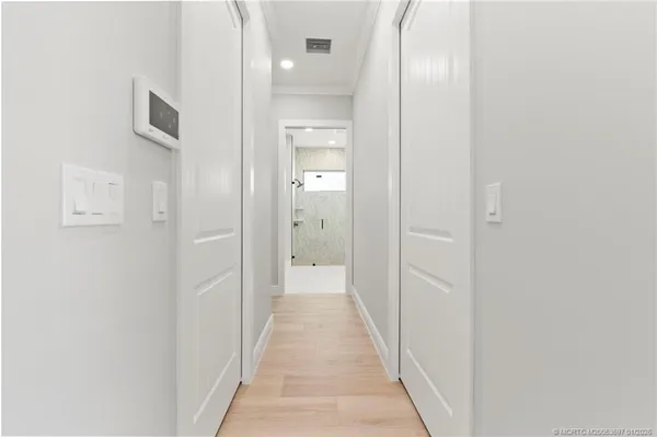 a view of a hallway with wooden floor and a bathroom