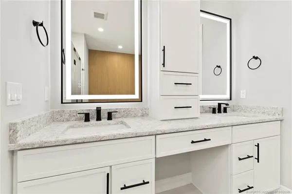 a bathroom with a granite countertop sink double vanity and a mirror