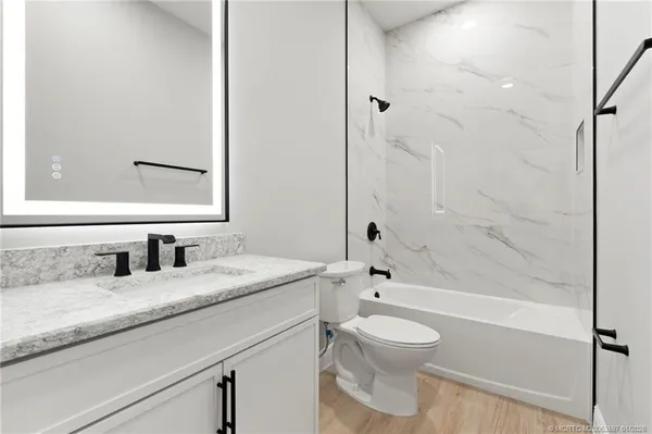 a bathroom with a granite countertop toilet a sink and a bathtub
