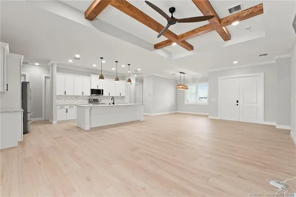 a view of an empty room with kitchen appliances and a ceiling fan