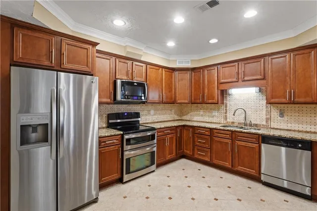 a kitchen with stainless steel appliances granite countertop a refrigerator a oven a sink with a dining table and chairs