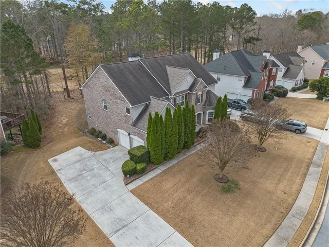an aerial view of a house with a yard and a large tree