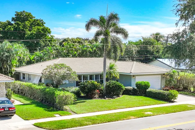 a front view of a house with a yard and potted plants