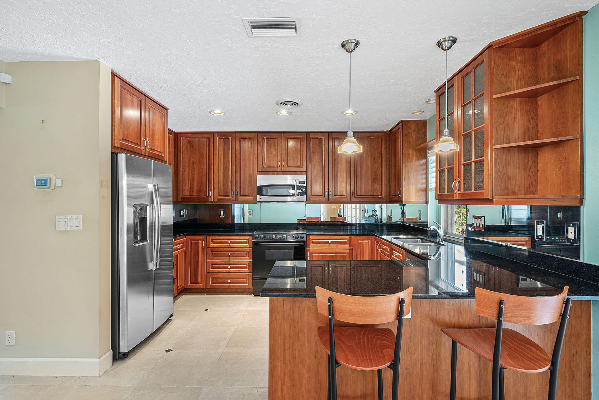 220 Southwest 9th Avenue Boca Raton, FL 33486 - Photo 13 of 42 a kitchen with stainless steel appliances granite countertop a refrigerator a sink dishwasher a stove and a dining table with wooden cabinet