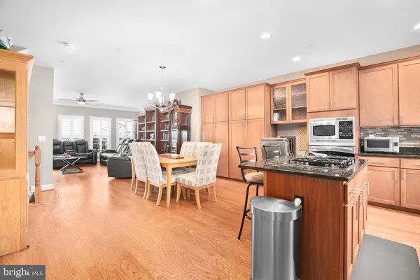 a dining hall with stainless steel appliances granite countertop a stove a sink a dining table and chairs with wooden floor